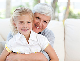 Mature woman hugging her granddaughter, all smiles