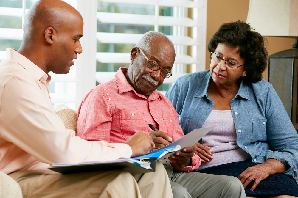 An adult man reviewing documents with his parents, sitting on a couch
