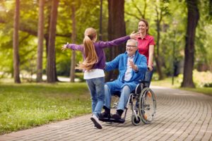cheerful grandfather in wheelchair welcoming his granddaughter