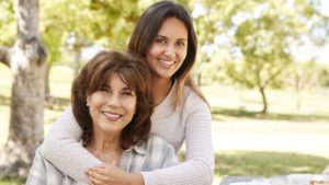 Senior mother and adult daughter embracing in park, close up