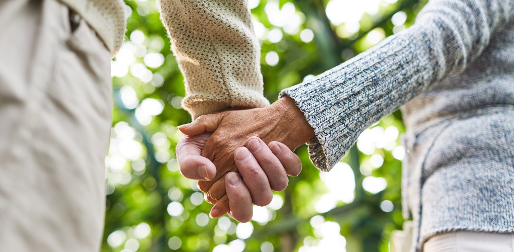 Family With Baby Daughter In Kitchen Using Laptop On Counter