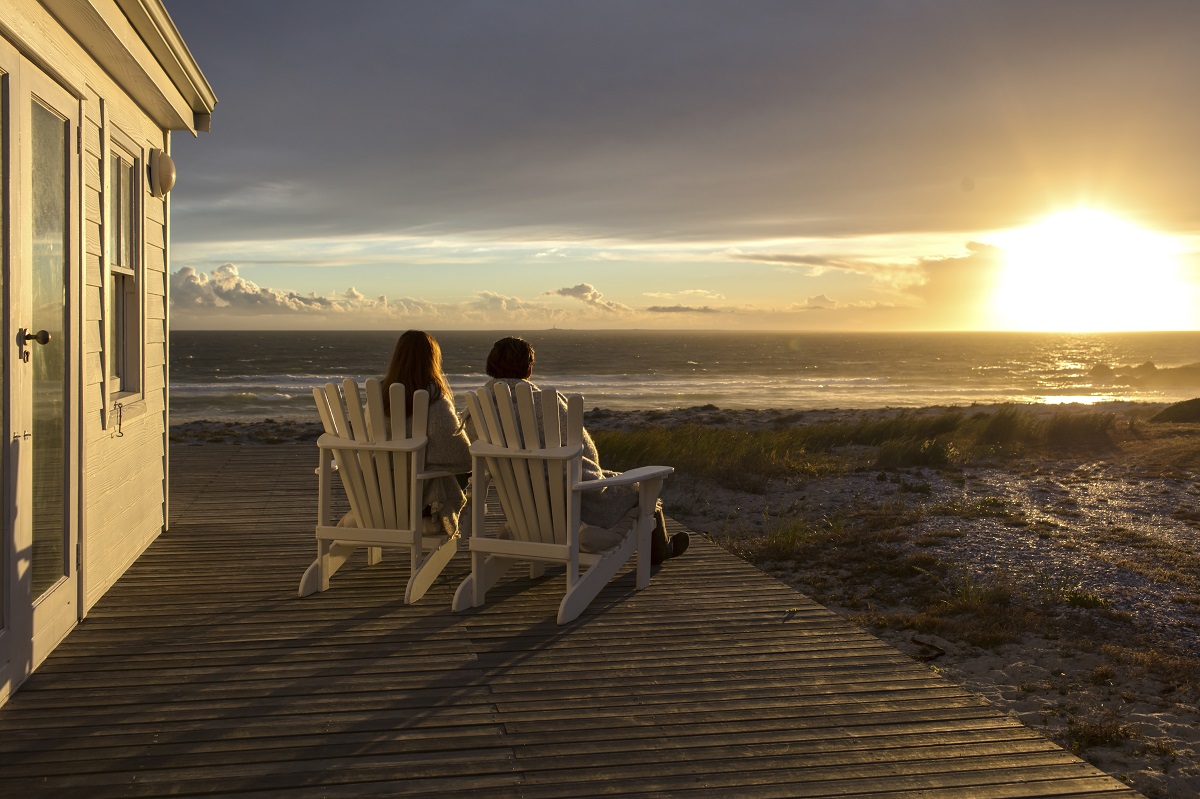 Couple watching sunset from the deck of their beach home