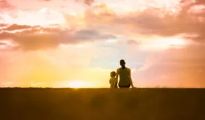 Adult and young child sitting together to watch sunset