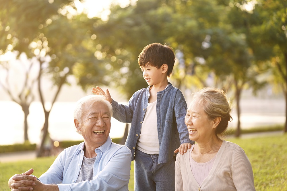 Senior couple on a park bench enjoying their young grandson