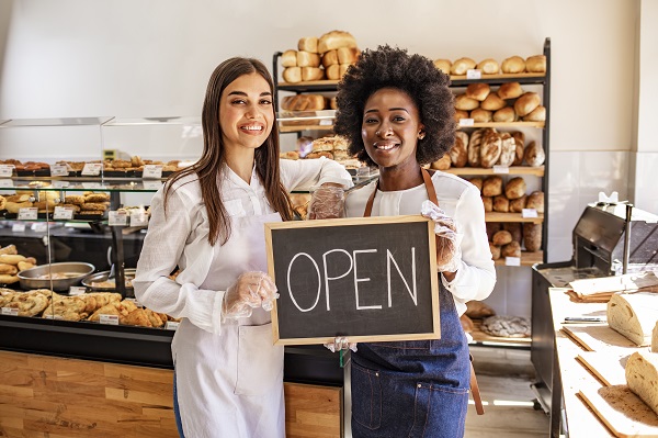 Young business women holding an open sign at their bakery