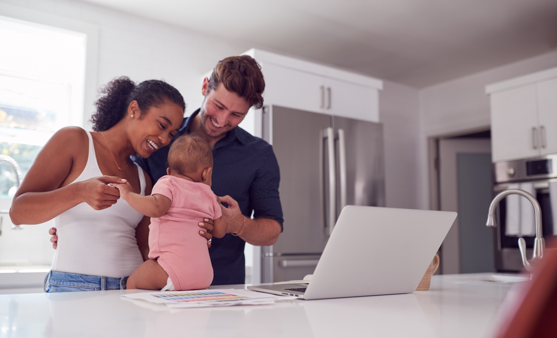 Young couple in the kitchen playing with a baby