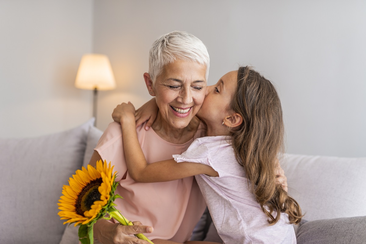 Happy little girl giving bouquet of flowers to her grandmother