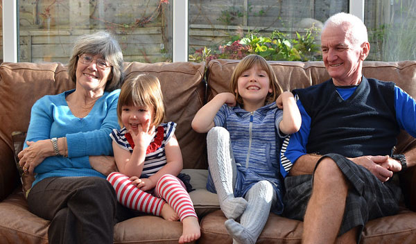 Grandmother and grandfather with 2 young children on a couch and laughing