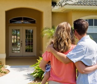 Young couple holding toddler and looking at the new home they purchased