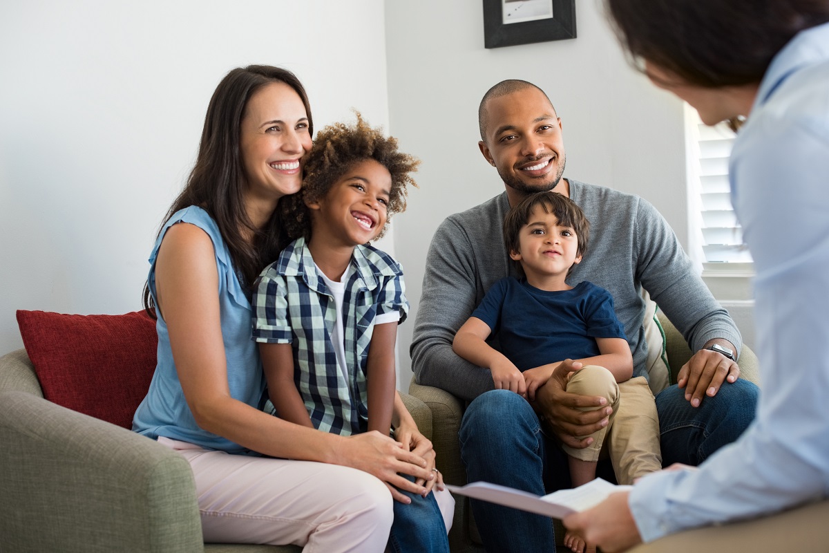 Happy young family with two children sitting on couch and talking with a lawyer