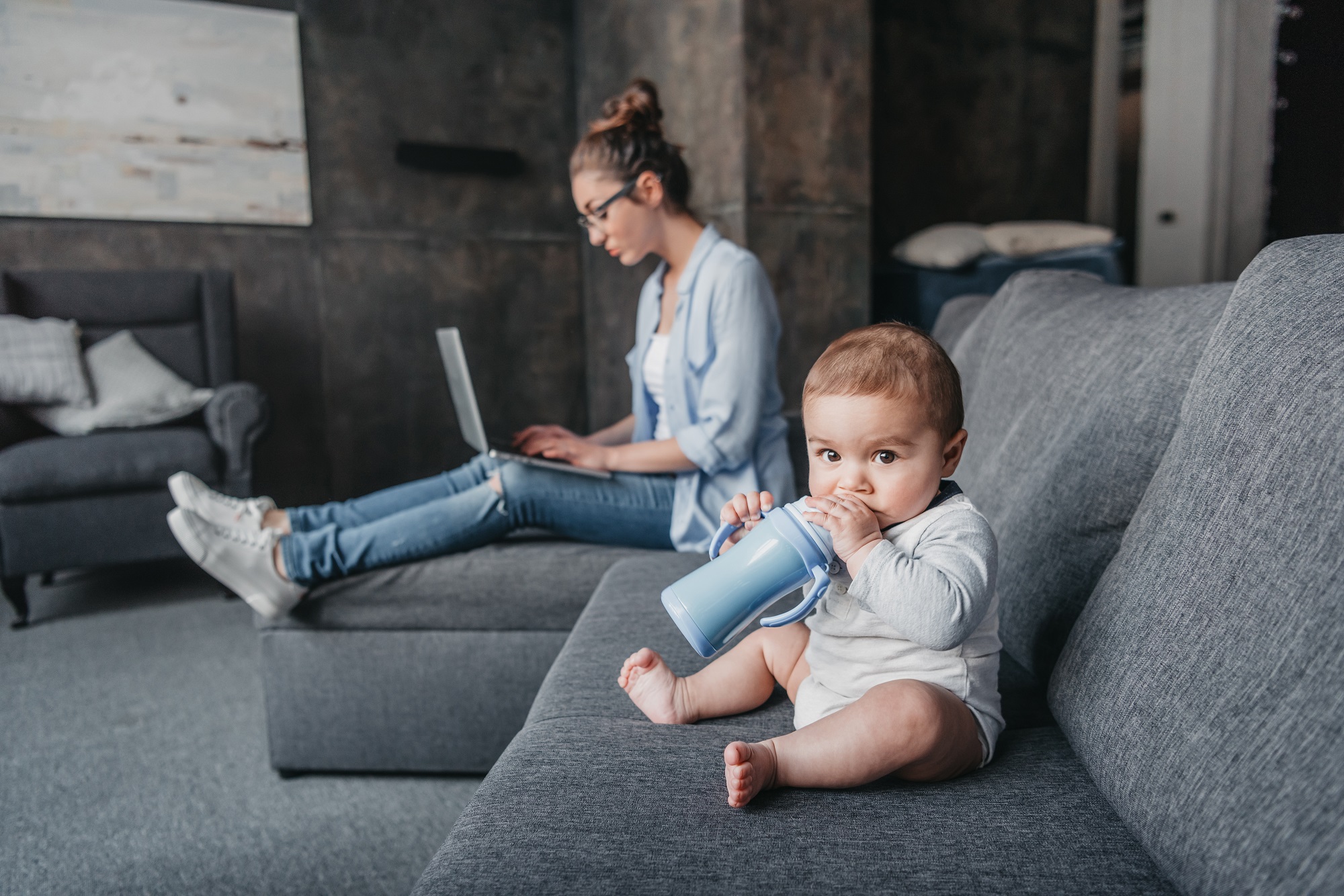 Estate planning from home, mother with laptop on her couch with her baby nearby