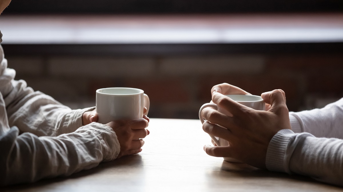 Man and woman having coffee to discuss medical preferences. Photo is close up of their hands holding the coffee cups