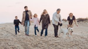 3-generation family walking with dog at seaside