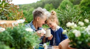 Happy senior grandmother with small granddaughter gardening in summer