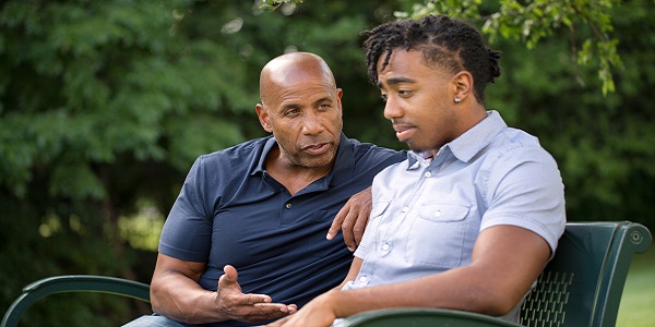 Somber father and his son talking while resting on a bench