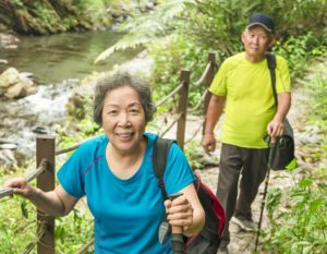 Smiling senior couple hiking along a riverside trail