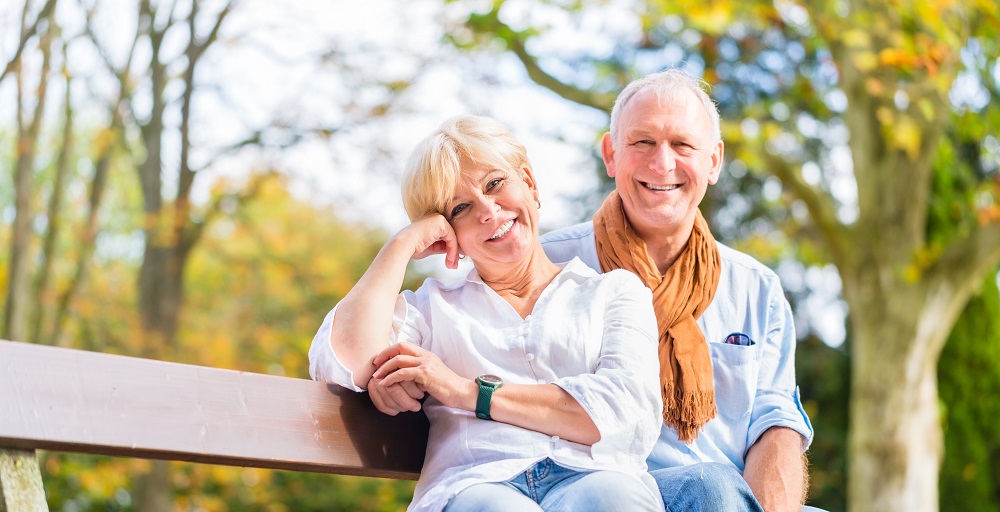 Senior woman and man sitting on park bench in fall