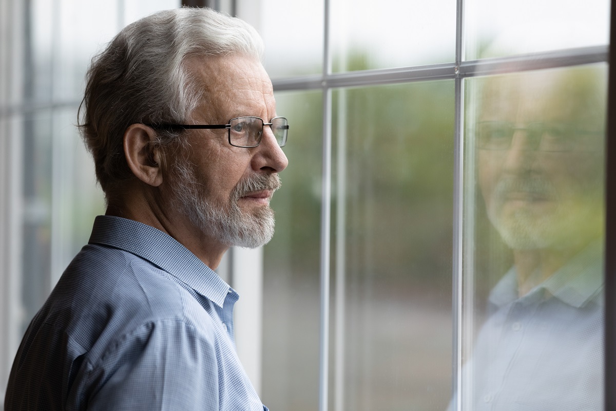 Pensive, mature man looking out window