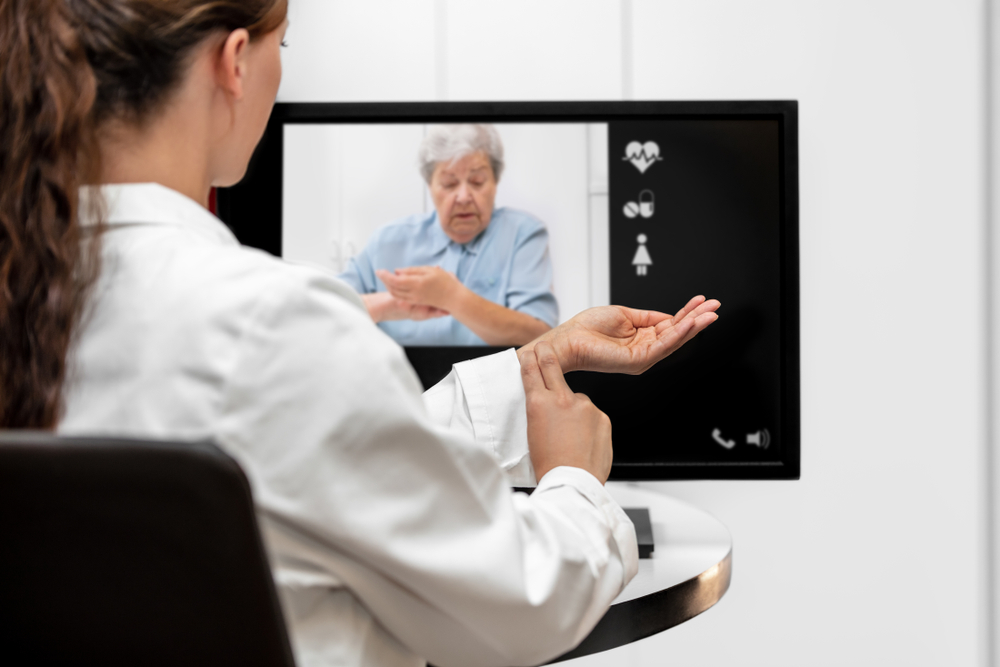 Doctor and senior woman taking the pulse together during a medicare telehealth video call